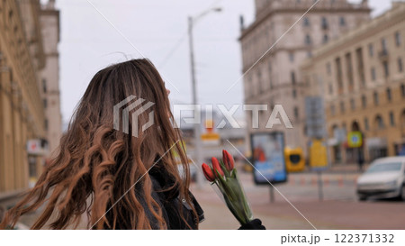 Hair of a girl with a bouquet of tulips in the city in the cold season. 122371332