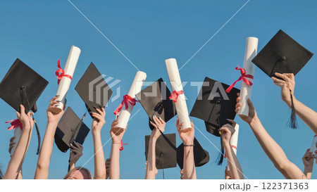 Group of students celebrating graduation by raising their diplomas and mortarboards to the sky Group of students celebrating graduation by raising their diplomas and mortarboards to the sky 122371363