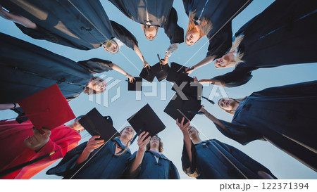 Students in a circle raising their graduation caps in celebration of their academic success Students in a circle raising their graduation caps in celebration of their academic success 122371394