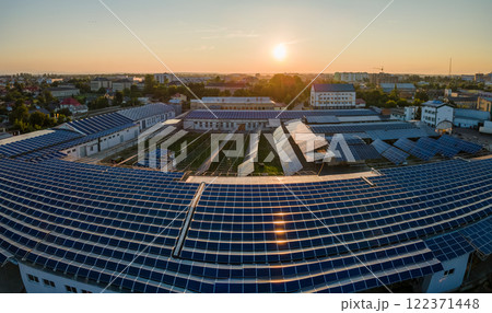 Aerial view of blue photovoltaic solar panels mounted on industrial building roof for producing green ecological electricity. Production of sustainable energy concept Aerial view of blue photovoltaic solar panels mounted on industrial building roof for producing green ecological electricity. Production of sustainable energy concept 122371448