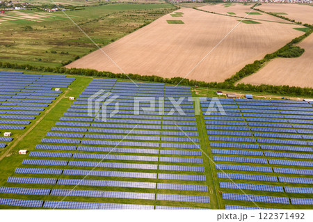 Aerial view of big sustainable electric power plant with many rows of solar photovoltaic panels for producing clean ecological electrical energy. Renewable electricity with zero emission concept. Aerial view of big sustainable electric power plant with many rows of solar photovoltaic panels for producing clean ecological electrical energy. Renewable electricity with zero emission concept. 122371492