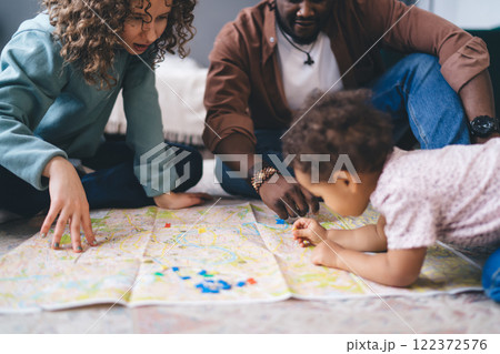 Crop serious parent and cute daughter coloring location on map over floor Crop serious parent and cute daughter coloring location on map over floor 122372576