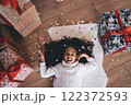 Excited black little girl lying on floor with gift boxes and colorful confetti 122372593