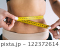 Slim woman measuring waist with tape 122372614