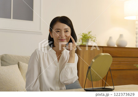 頬を人差し指で触る50代の女性 122373629