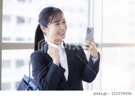 就活　スマホを見ながら喜ぶ女性 122374456