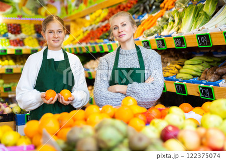 Girl helping her mother work as a salesman in a grocery store 122375074