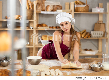 Pretty female baker preparing croissant dough - kneading dough with hands 122375225