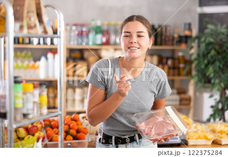 Young woman choosing raw pork in grocery store 122375284
