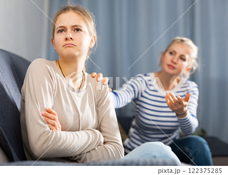 Sad female and daughter sitting at sofa and having quarrel 122375285