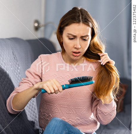 Frustrated young woman combs her hair 122375482