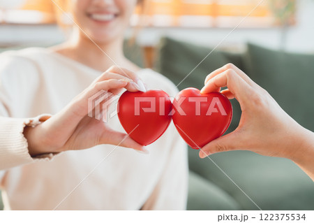 Closeup view of red heart on woman and man hands Closeup view of red heart on woman and man hands 122375534
