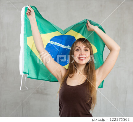 Happy woman posing with flag of Brazil on gray background 122375562
