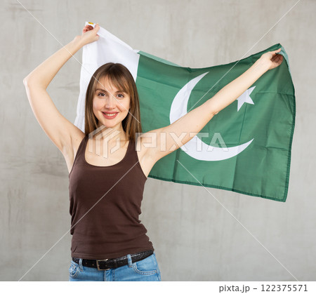Smiling woman waving flag of Pakistan against gray background Smiling woman waving flag of Pakistan against gray background 122375571