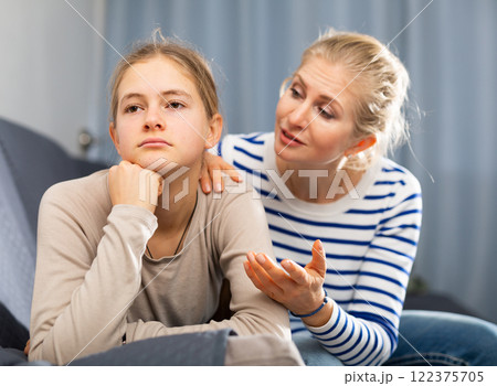 Sad female and daughter sitting at sofa and having quarrel 122375705