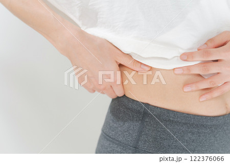 お腹の贅肉をつまむ女性 122376066