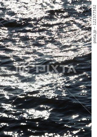 The shimmering water surface dances with sunlight reflections creating a tranquil scene 122377582