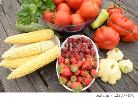 harvested vegetables. Tomatoes, corn, berries, eggplant on a wooden dark background 122377876
