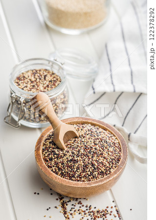 Mixed uncooked quinoa seeds in bowl on white table. 122378292