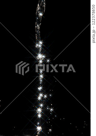 Shining water created sparkling splash with bright reflections and starburst flare, like  star in light. Water Glitter from splash caught light, creating abstract sparkling scene with star flare 122378650