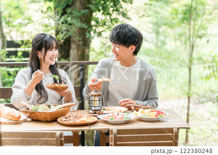 ウッドデッキ・テラス席・バルコニー席で食事するカップル・夫婦(グランピング・ベランピング) ウッドデッキ・テラス席・バルコニー席で食事するカップル・夫婦(グランピング・ベランピング) 122380248