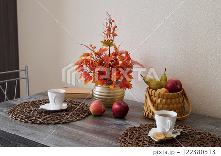 A Beautiful Autumn Table Setting Featuring an Elegantly Arranged Display of Flowers and Fresh Fruits 122380313