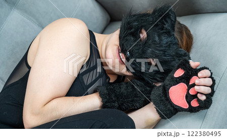 A woman in a cat costume lies on a gray sofa. Quadrober. A woman in a cat costume lies on a gray sofa. Quadrober. 122380495