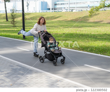 Caucasian woman roller skating with her toddler son in a stroller.  122380502