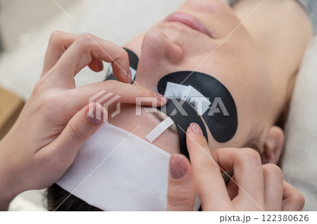 The master applies protective patches that do not let in ultraviolet rays before LED eyelash extensions. The master applies protective patches that do not let in ultraviolet rays before LED eyelash extensions. 122380626