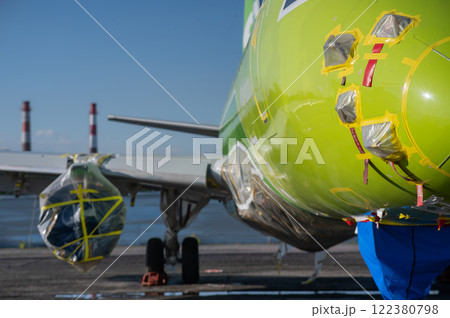 Airplane undergoing repairs in the open air. 122380798
