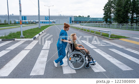 Profile of a nurse helping an elderly woman in a wheelchair cross the road. Profile of a nurse helping an elderly woman in a wheelchair cross the road. 122380800