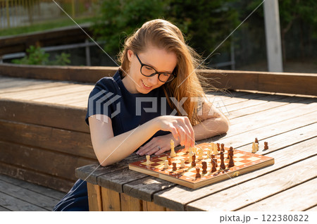 Caucasian woman playing chess outdoors. 122380822