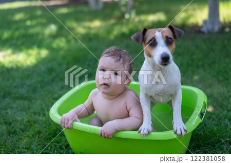 Cute boy bathes in a basin with a Jack Russell terrier dog outdoors in the summer. 122381058