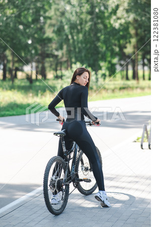 Rear view of Caucasian woman riding bike in park. Vertical photo. Rear view of Caucasian woman riding bike in park. Vertical photo. 122381080