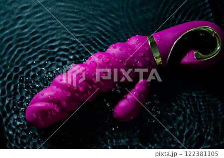 Pink ribbed vibrator in water. Circles on water around sex toy.  122381105