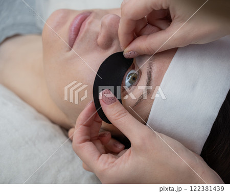 The master applies protective patches that do not let in ultraviolet rays before LED eyelash extensions. The master applies protective patches that do not let in ultraviolet rays before LED eyelash extensions. 122381439