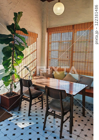 restaurant table and chairs  by tree and natural light from window 122381486