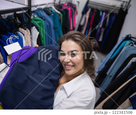 Top view of a chubby-cheeked woman holding an armful of clothes in a plus size store. Top view of a chubby-cheeked woman holding an armful of clothes in a plus size store. 122381506