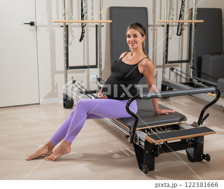 Pregnant woman resting after Pilates on a reformer machine. Pregnant woman resting after Pilates on a reformer machine. 122381666