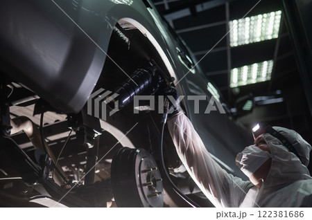 The master sprays an anti-corrosion compound on the bottom of the car.  122381686