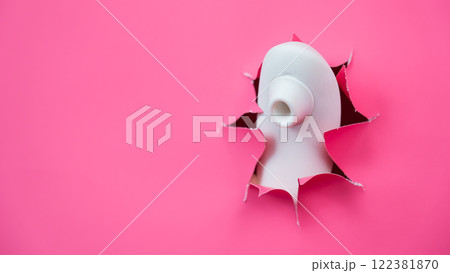 White vacuum clitoral vibrator sticking out through pink paper background. Sex toy. White vacuum clitoral vibrator sticking out through pink paper background. Sex toy. 122381870