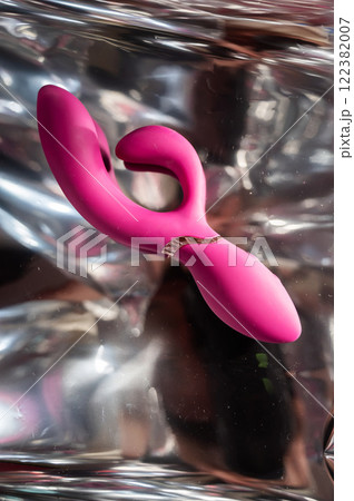 Sex toy on a metal background in the reflections of light.  122382007