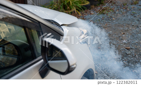 Smoke is coming from under the hood of the car.  122382011