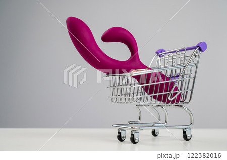 Sex toy in miniature shopping cart on white background.  122382016