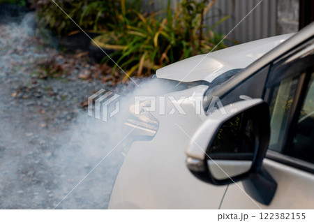 Smoke is coming from under the hood of the car. Smoke is coming from under the hood of the car. 122382155