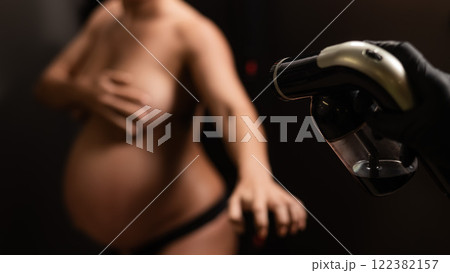 The master applies bronzer with a spray on the hands of a pregnant woman. Instant tan. The master applies bronzer with a spray on the hands of a pregnant woman. Instant tan. 122382157