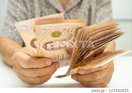 Asian elder senior woman patient holding Thai banknotes money in her hand, Cost of living and medical care. 122382635