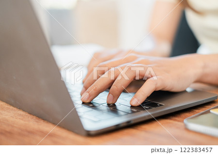Hands typing on a laptop keyboard in a well-lit workspace, ideal for business, education, or remote work themes. 122383457