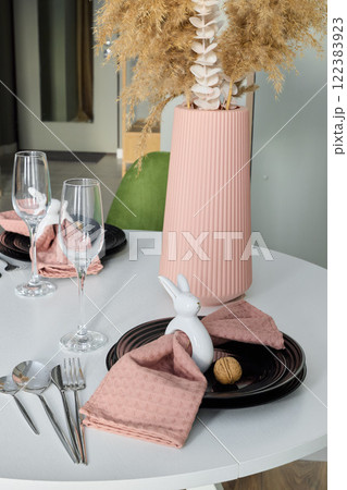 An Elegant Table Setting featuring a Decorative Rabbit alongside a Floral Centerpiece 122383923