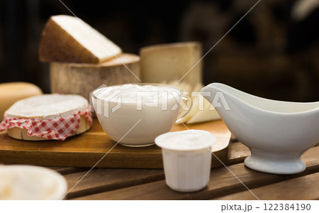 Milk, cottage cheese, cream, cheese on table against background of cows Milk, cottage cheese, cream, cheese on table against background of cows 122384190